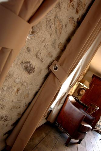 a room with a table and a chair and a wall at Hotel L'Aunette Cottage in Chamant