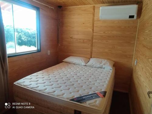 ein kleines Bett in einem kleinen Zimmer mit Fenster in der Unterkunft Casa Container Azul. in Bagé