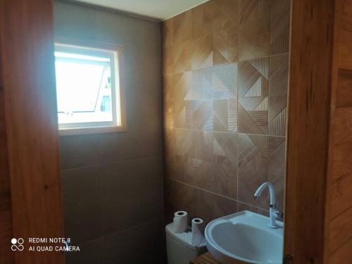 een badkamer met een wastafel, een toilet en een raam bij Casa Container Azul. in Bagé