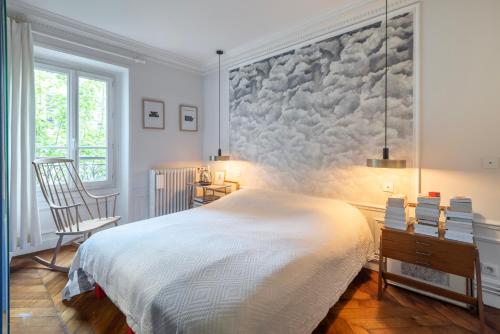 une chambre avec un grand lit et une chaise dans l'établissement Appartement Unique - Art et Charme Paris 17ème, à Paris
