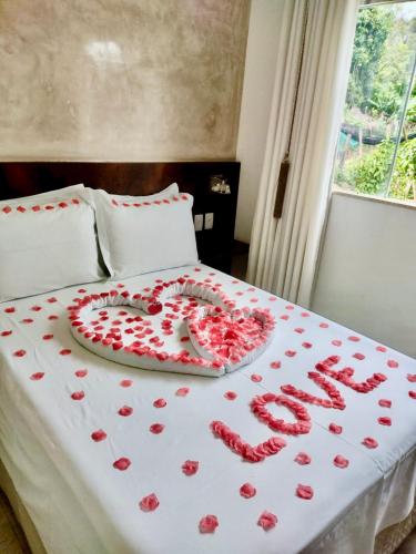 a bed with a heart made out of red roses at Lara's Home Suites in Capitólio