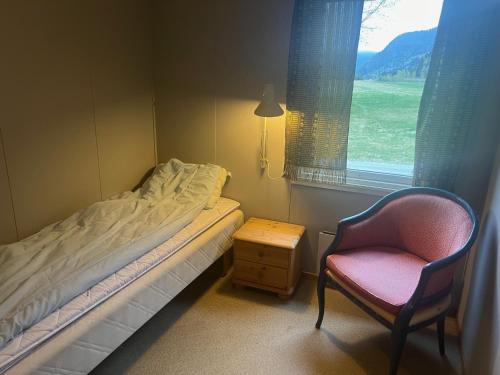 a bedroom with a bed and a chair and a window at Reiårsfossen Hostel & Camping in Bygland
