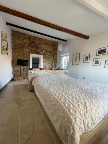 1 dormitorio con 1 cama grande y pared de piedra en La Petite Fenêtre, en Casale Marittimo