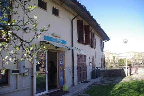a white building with a woman standing in the doorway at Acqua Piatta - L'Ostello del Canoa in Ivrea