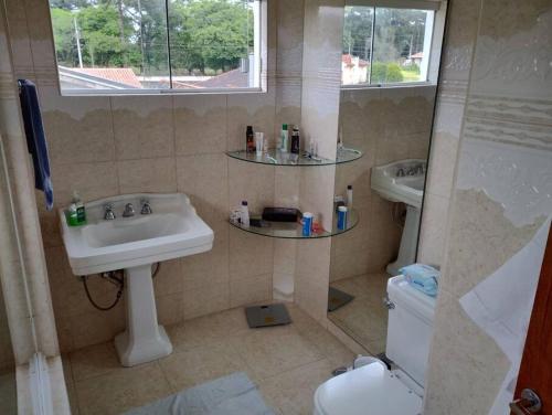 een badkamer met een wastafel, een toilet en een raam bij casa de campo, dentro do urbano. in Piraquara