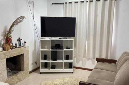 een woonkamer met een flatscreen-tv op een witte kast bij casa de campo, dentro do urbano. in Piraquara