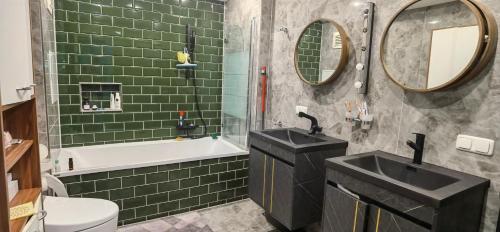 een badkamer met groene tegels, een bad en een wastafel bij Joy's home in Bad Homburg vor der Höhe