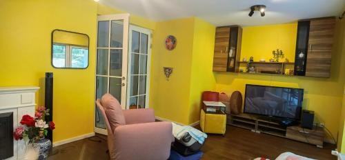 een woonkamer met gele muren en een tv bij Joy's home in Bad Homburg vor der Höhe