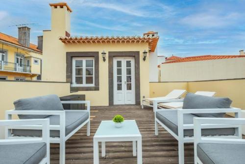 a patio with chairs and a table and a house at Studios Funchal in Funchal