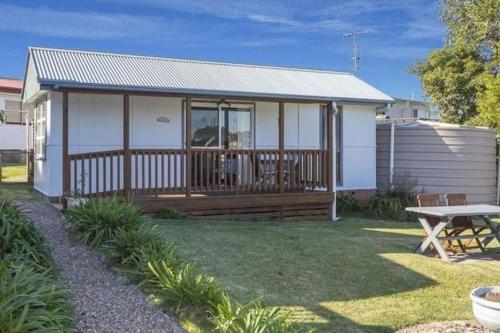a white house with a deck and a picnic table at North Durras Beach Cottage in Durras