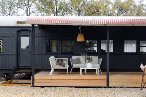 a black trailer with two chairs and a table on a deck at The Station Hunter Valley in Pokolbin