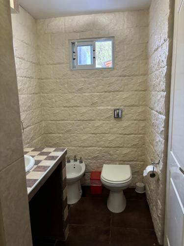 uma casa de banho com um WC, um lavatório e uma janela em Robinson Apartamentos SOLO FAMILIAS em Villa Carlos Paz
