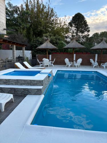 uma piscina com cadeiras e guarda-sóis num pátio em Robinson Apartamentos SOLO FAMILIAS em Villa Carlos Paz