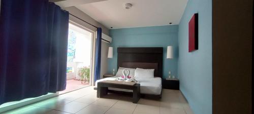 a bedroom with a bed and a large window at Hotel BLVD in Playa del Carmen