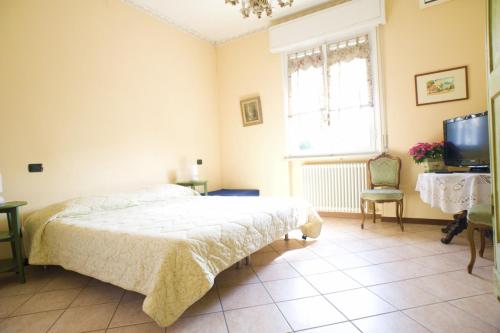 Schlafzimmer mit einem Bett, einem TV und einem Fenster in der Unterkunft B&B Alla Villa in Parma