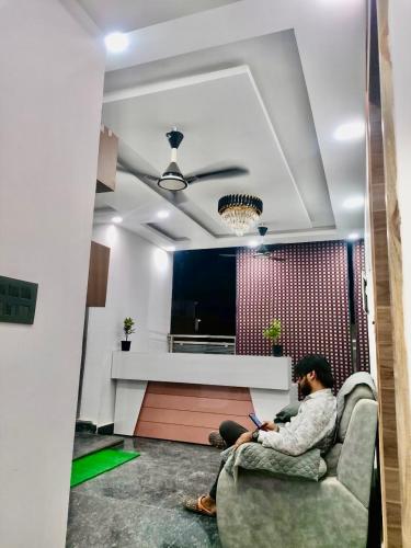 un homme assis sur un canapé dans un salon avec un ordinateur portable dans l'établissement Hotel Super inn, à Mathura