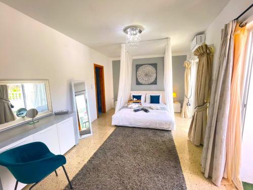 a bedroom with a bed with a blue chair and a mirror at 5 mins near Sea Cozy Luxury 3 Balconies South Views in Mellieħa