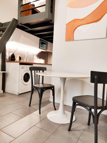 une cuisine avec une table et deux chaises ainsi qu'un lave-linge dans l'établissement Appartement dans le centre historique, à Bordeaux