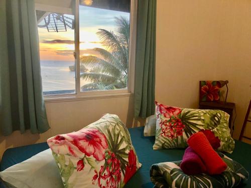 a bedroom with a window and a bed with pillows at Fare Mirimiri in Uturoa