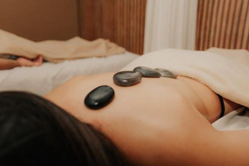 a woman laying on a bed with rocks on her back at Serra Negra Pousada Spa in Guarapari