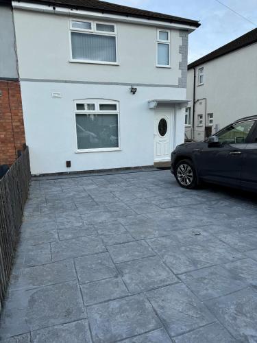 un coche aparcado frente a una casa blanca en Home away from home en Leicester