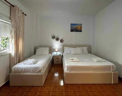 two twin beds in a room with a window at Nardi Guesthouse in Ksamil