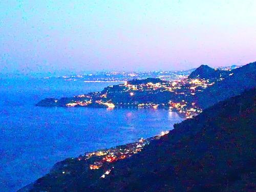 uma vista da cidade e do oceano à noite em Casa Francesco em Forza dʼAgro