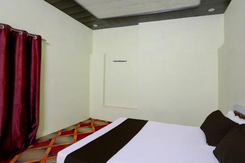 a bedroom with a white bed with red curtains at SPOT ON Mahadev Hotel in Prayagraj