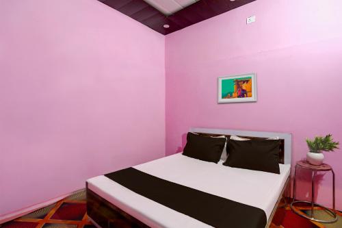 a bedroom with a pink wall with a bed in it at SPOT ON Mahadev Hotel in Prayagraj