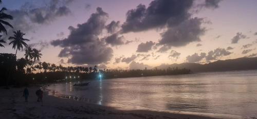 twee mensen lopen op het strand bij zonsondergang bij Dreamvilles Ecovillage Las Galeras in Las Galeras