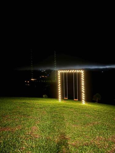 a building with lights on it in a field at night at Domo Geodésico - Entre Chalés - Pet Friendly in São Bento do Sapucaí