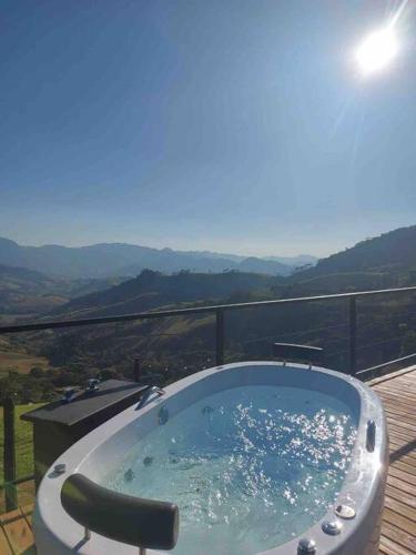 a jacuzzi tub on a balcony with a view at Domo Geodésico - Entre Chalés - Pet Friendly in São Bento do Sapucaí