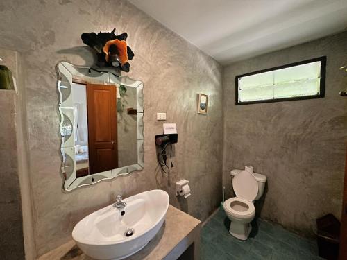 a bathroom with a sink and a toilet and a mirror at Pairadise Hotel in Pai