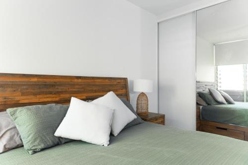 um quarto com uma cama com almofadas brancas em Breezy Treetop Escape in Stuart Park em Stuart Park