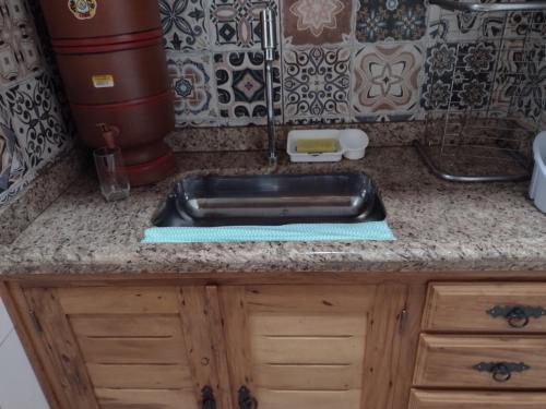 um balcão de cozinha com um lavatório preto em Aconchego Mineiro em São João del Rei