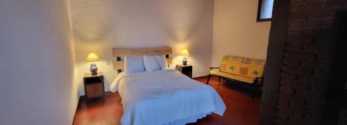 ein Schlafzimmer mit einem Bett mit weißer Bettwäsche und zwei Lampen in der Unterkunft Alojamiento El Fresno in Mineral del Chico