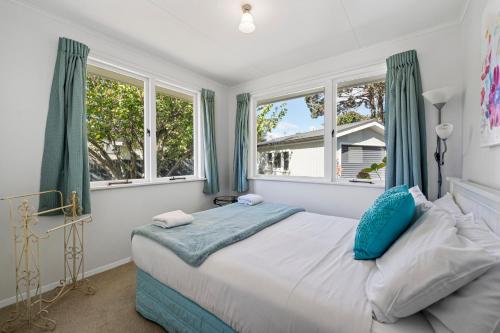 a bedroom with a bed with green curtains and windows at Tui Paradise - Havelock North in Havelock North