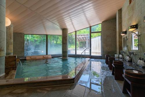 een groot zwembad met water in een kamer met ramen bij Gyokusui -Adult Only- in Higashiizu