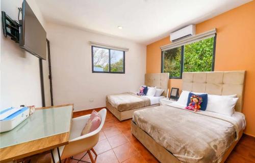 Pokój z 2 łóżkami, biurkiem i telewizorem w obiekcie Villa Cancún w mieście Cancún