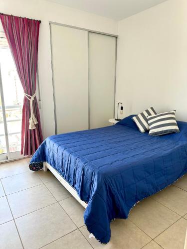 a blue bed in a room with a window at Cálido y céntrico departamento 2 opcional cochera in Bahía Blanca