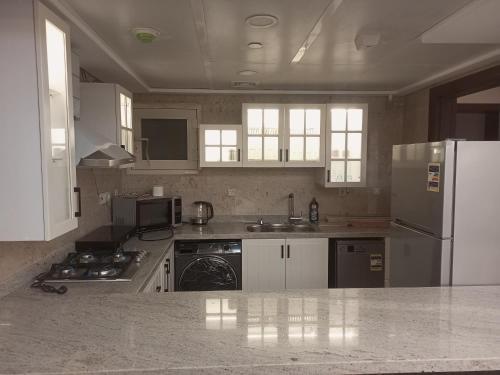 a kitchen with white cabinets and a refrigerator at شقة فندقية في فندق هيلتون المعادي علي الكورنيش مباشرة in Cairo