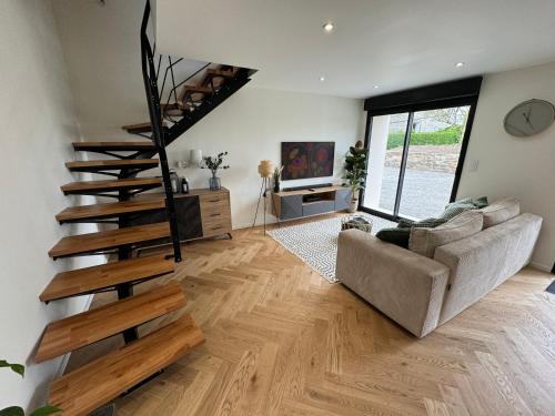 a living room with a staircase and a couch at Maison bretonne en pierre rénovée in Plédran
