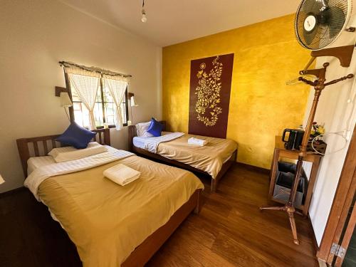 two beds in a room with yellow walls at Pairadise Hotel in Pai
