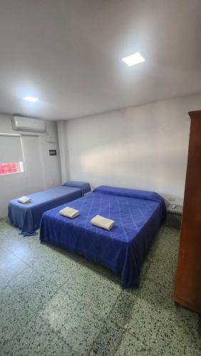 um quarto com duas camas com lençóis azuis em Habitacion con baño em Termas de Rio Hondo