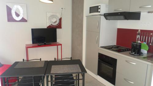 a small kitchen with a table and a refrigerator at Gîtes Macarien in Saint-Macaire