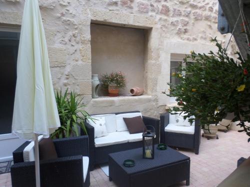 a patio with chairs and an umbrella and a table at Gîtes Macarien in Saint-Macaire