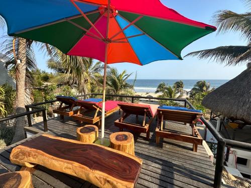 a patio with tables and an umbrella on the beach at Beachfront Paradise Boutique Hotel in Santa María Tonameca