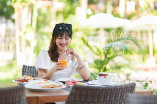 uma mulher sentada numa mesa com um copo de sumo de laranja em Touch Sea Boutique Hotel&Bistro em Ka Rorn