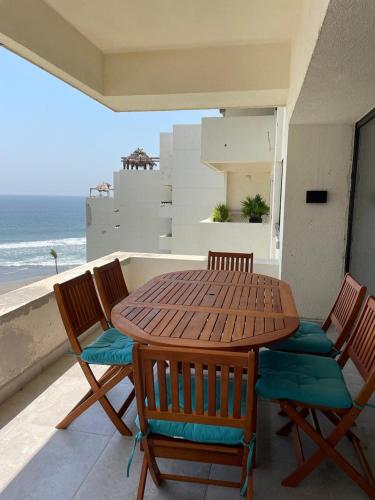 a wooden table and chairs on a balcony with the ocean at Increíble depto. en playa privada. in Acapulco