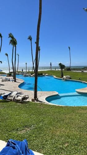 a large swimming pool with palm trees and a beach at Increíble depto. en playa privada. in Acapulco